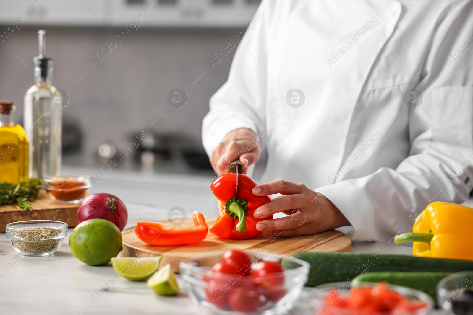 Photo of Professional chef cutting pepper at table in kitchen, closeup