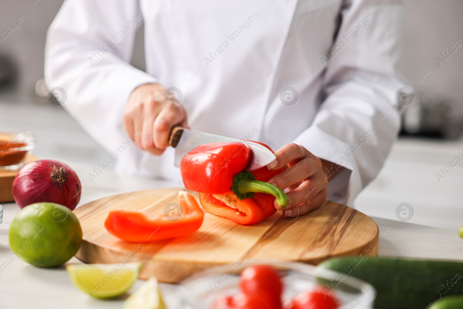 Photo of Professional chef cutting pepper at table in kitchen, closeup