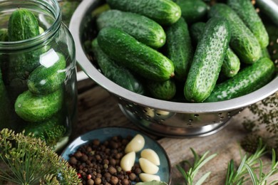 Photo of Fresh cucumbers, herbs and spices on wooden table, closeup. Preparation for pickling