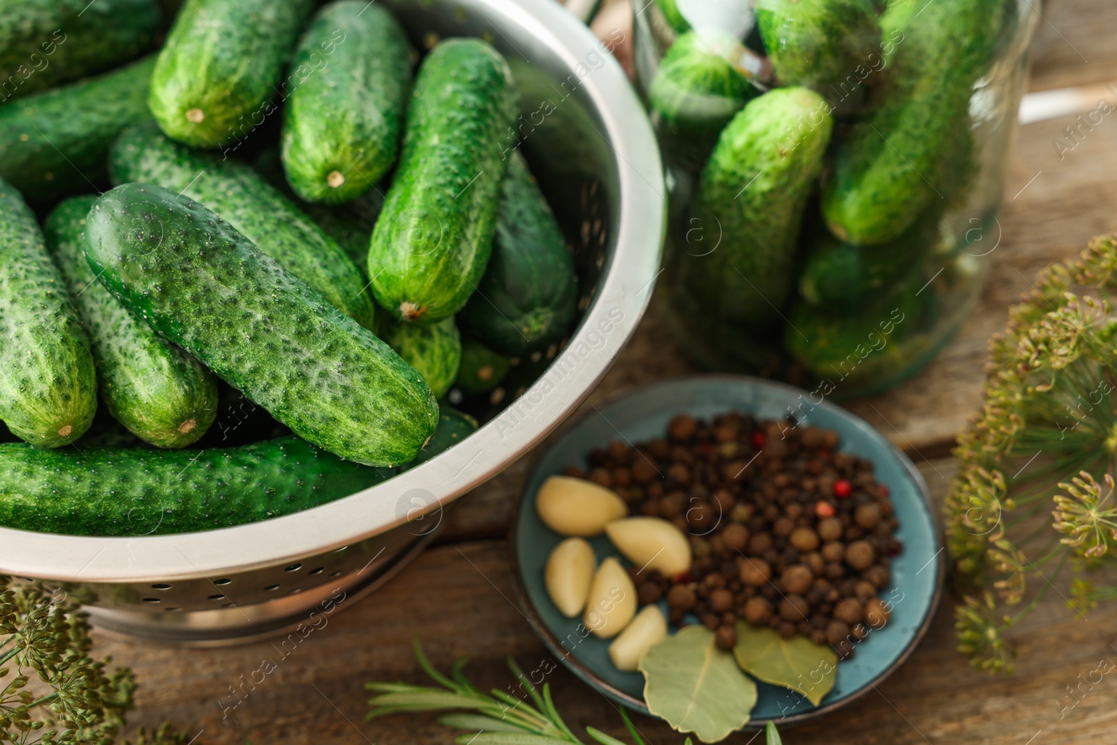 Photo of Fresh cucumbers, herbs and spices on wooden table, closeup. Preparation for pickling