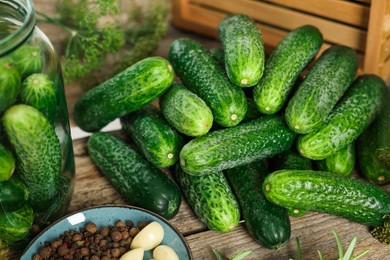 Photo of Pile of fresh cucumbers and spices on wooden table, closeup. Preparation for pickling