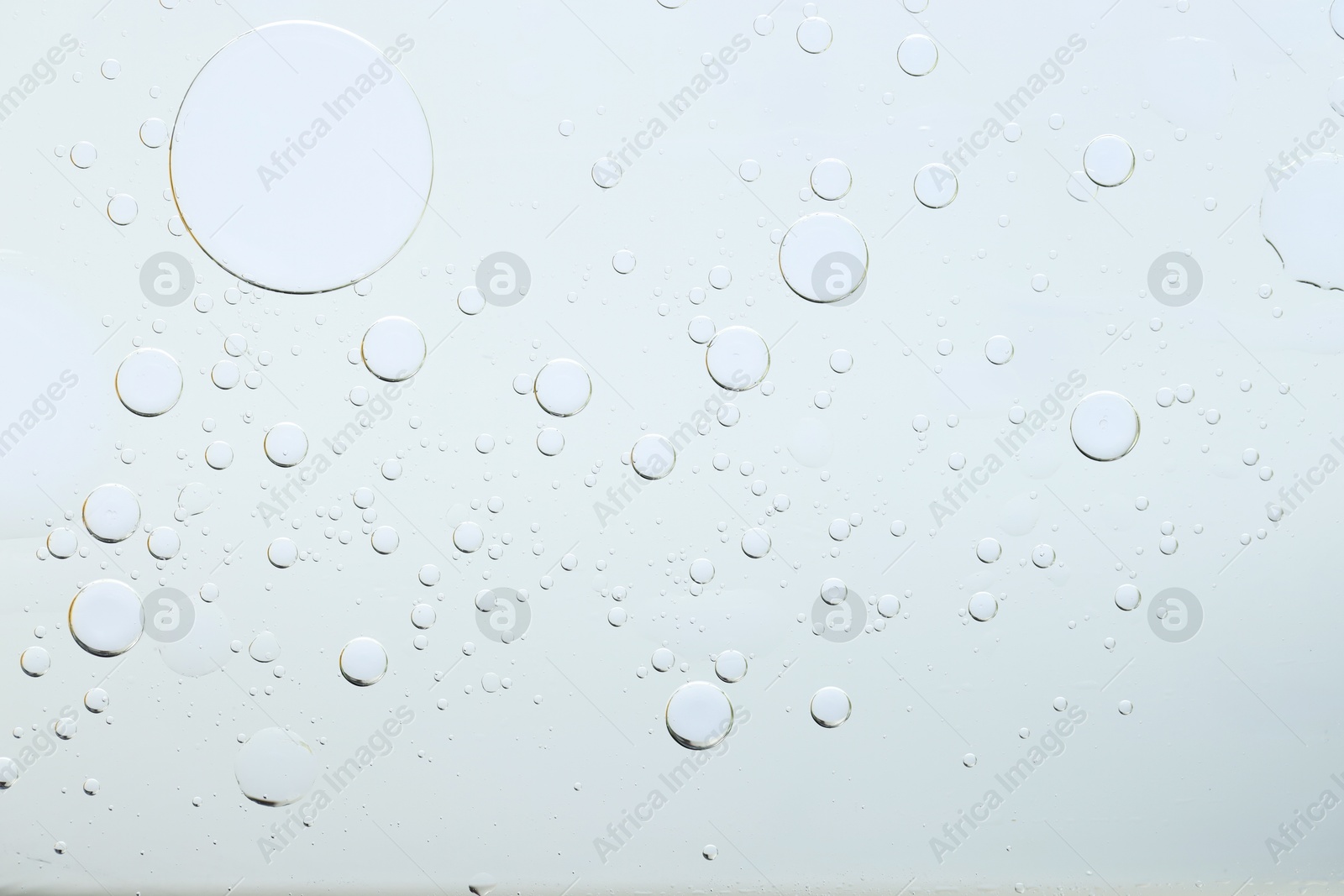 Photo of Sample of cosmetic oil on light grey background, macro view