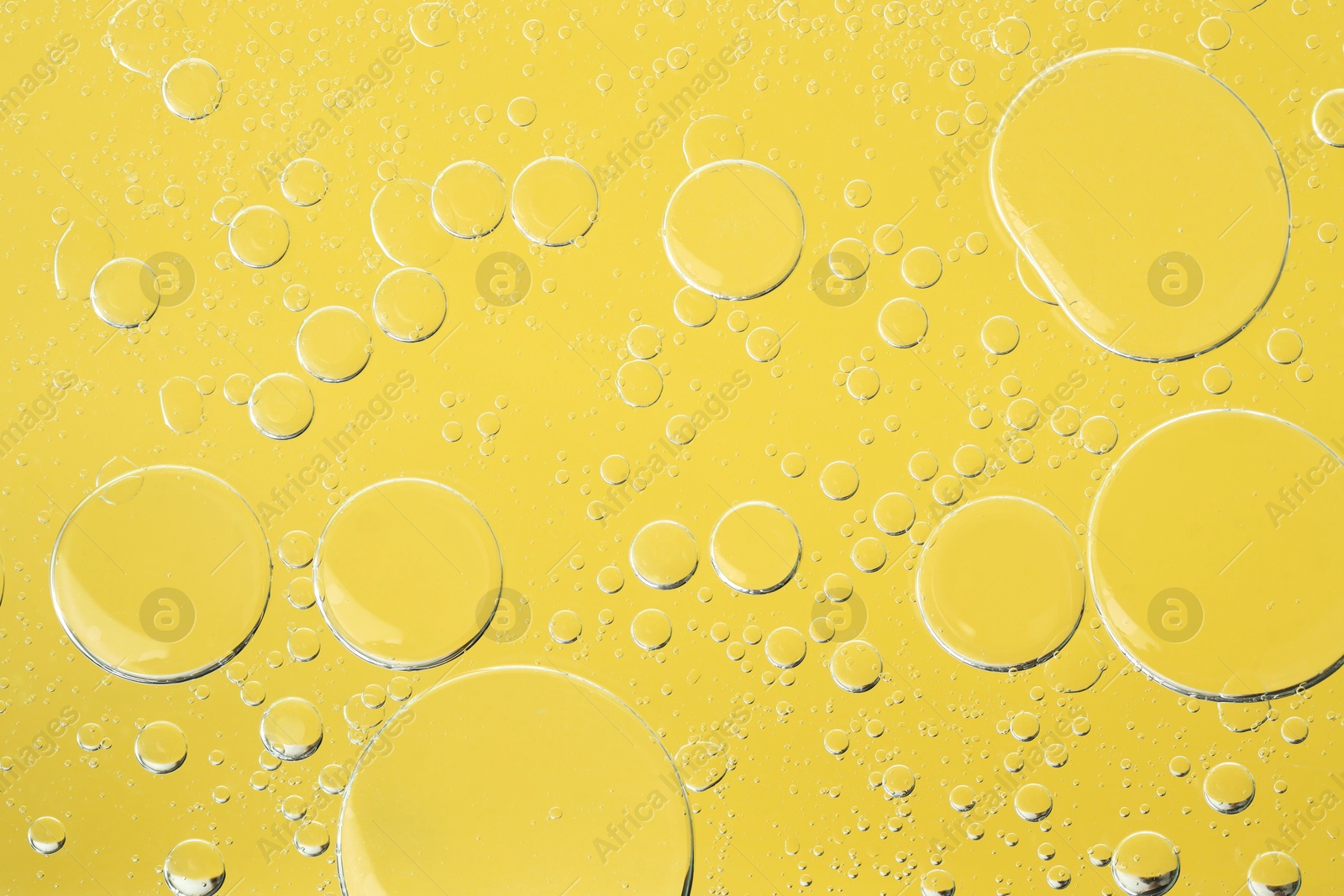 Photo of Sample of cosmetic oil on yellow background, macro view