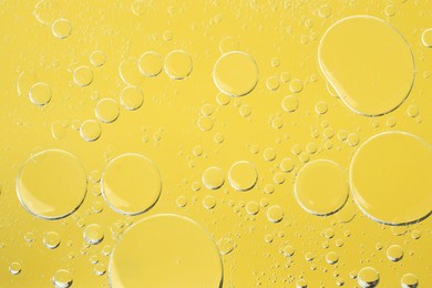 Photo of Sample of cosmetic oil on yellow background, macro view