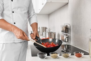 Photo of Professional chef cooking delicious food on stove in kitchen, closeup