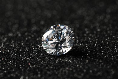 Photo of Beautiful dazzling diamond on dark shiny background, closeup