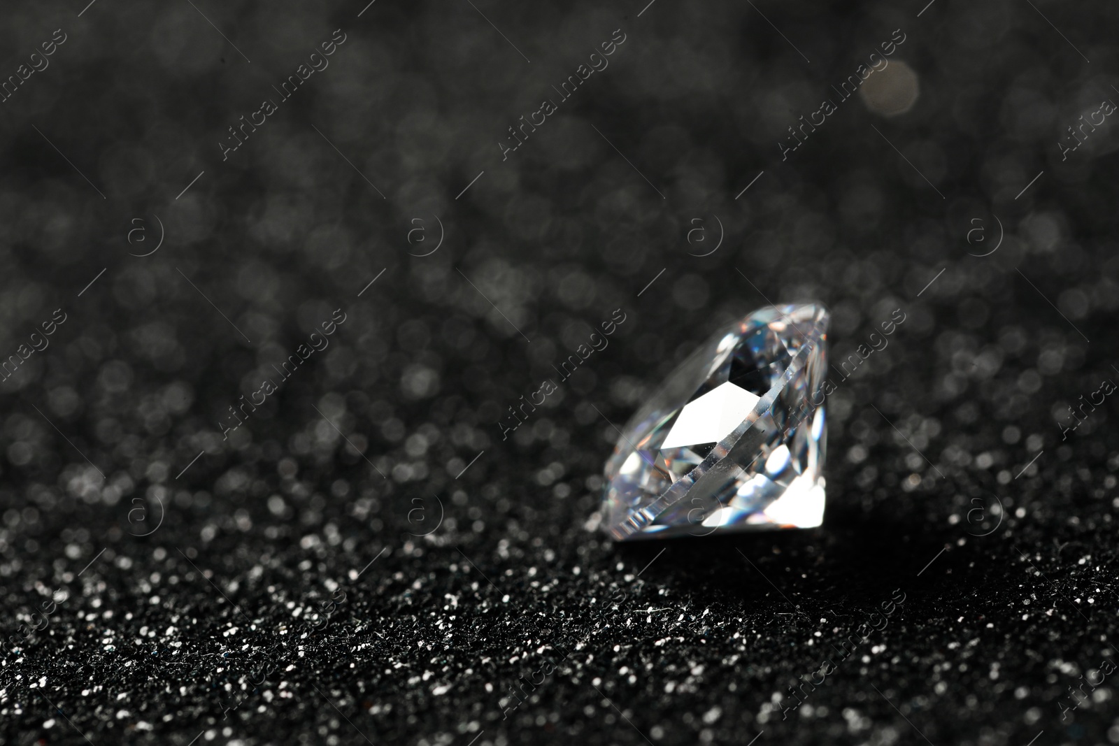 Photo of Beautiful dazzling diamond on dark shiny background, closeup. Space for text