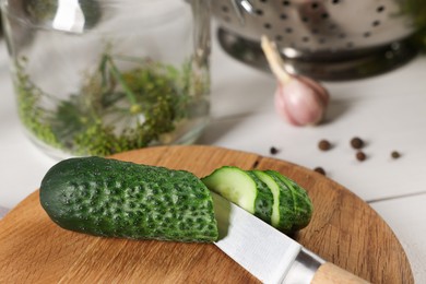 Photo of Board with fresh cut cucumber and knife on light table, closeup