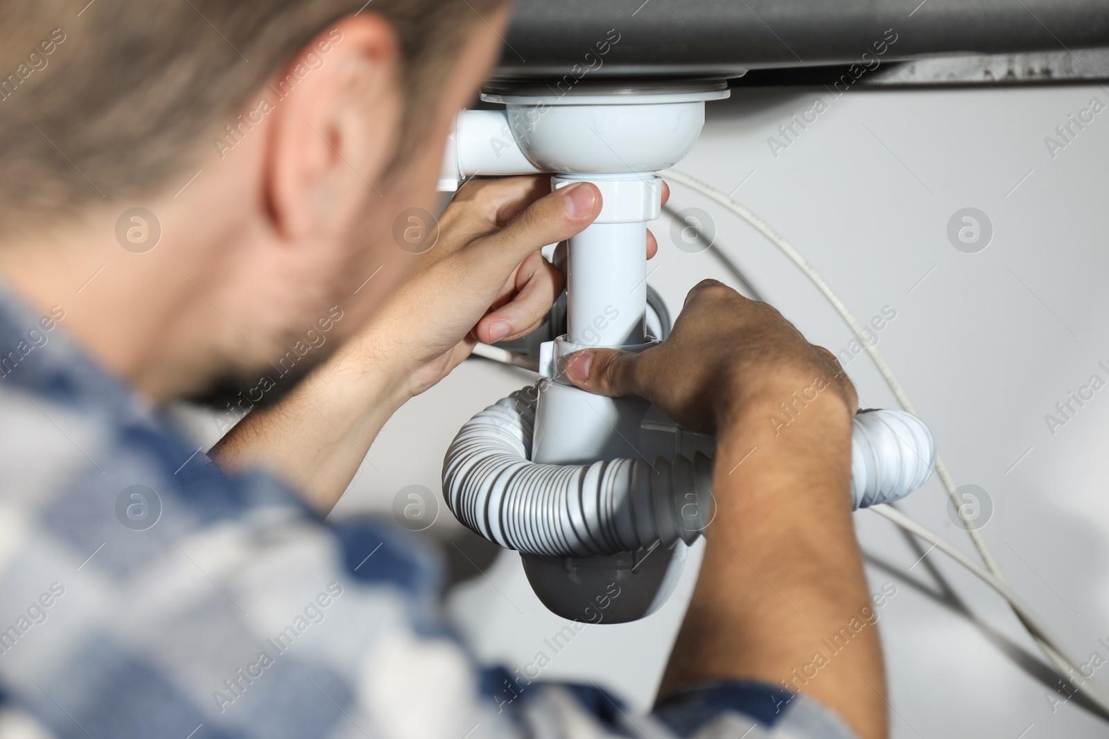 Photo of Professional plumber fixing piping system at home, closeup