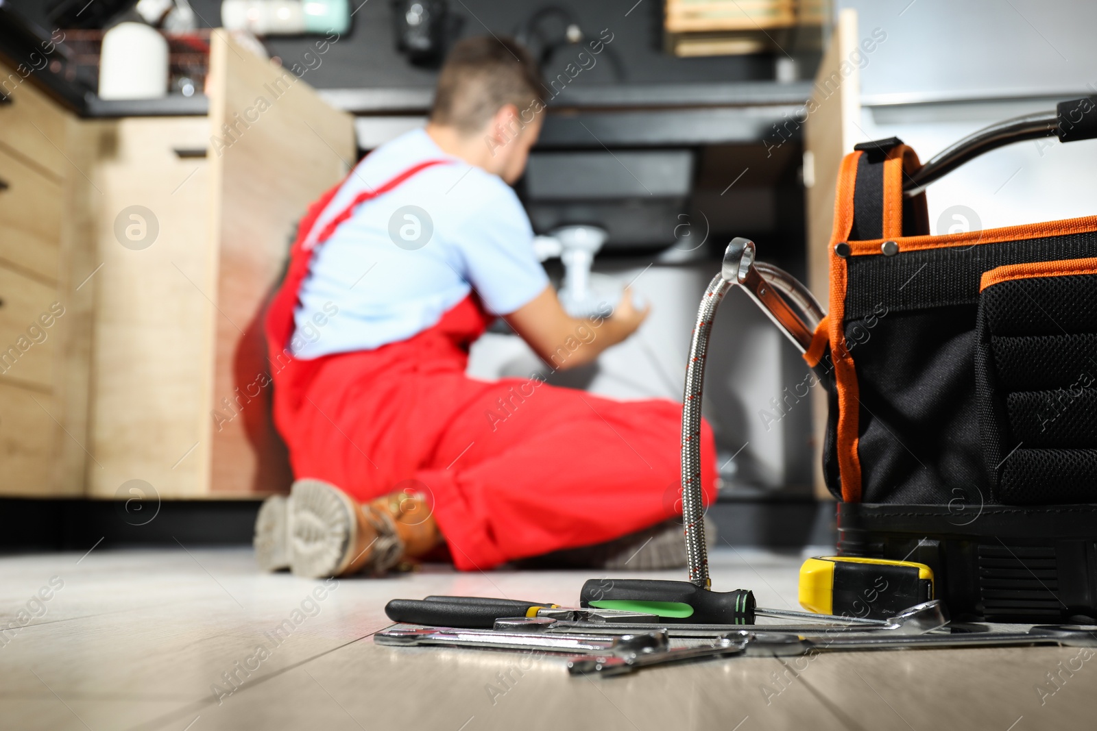 Photo of Professional plumber fixing piping system at home, focus on tools