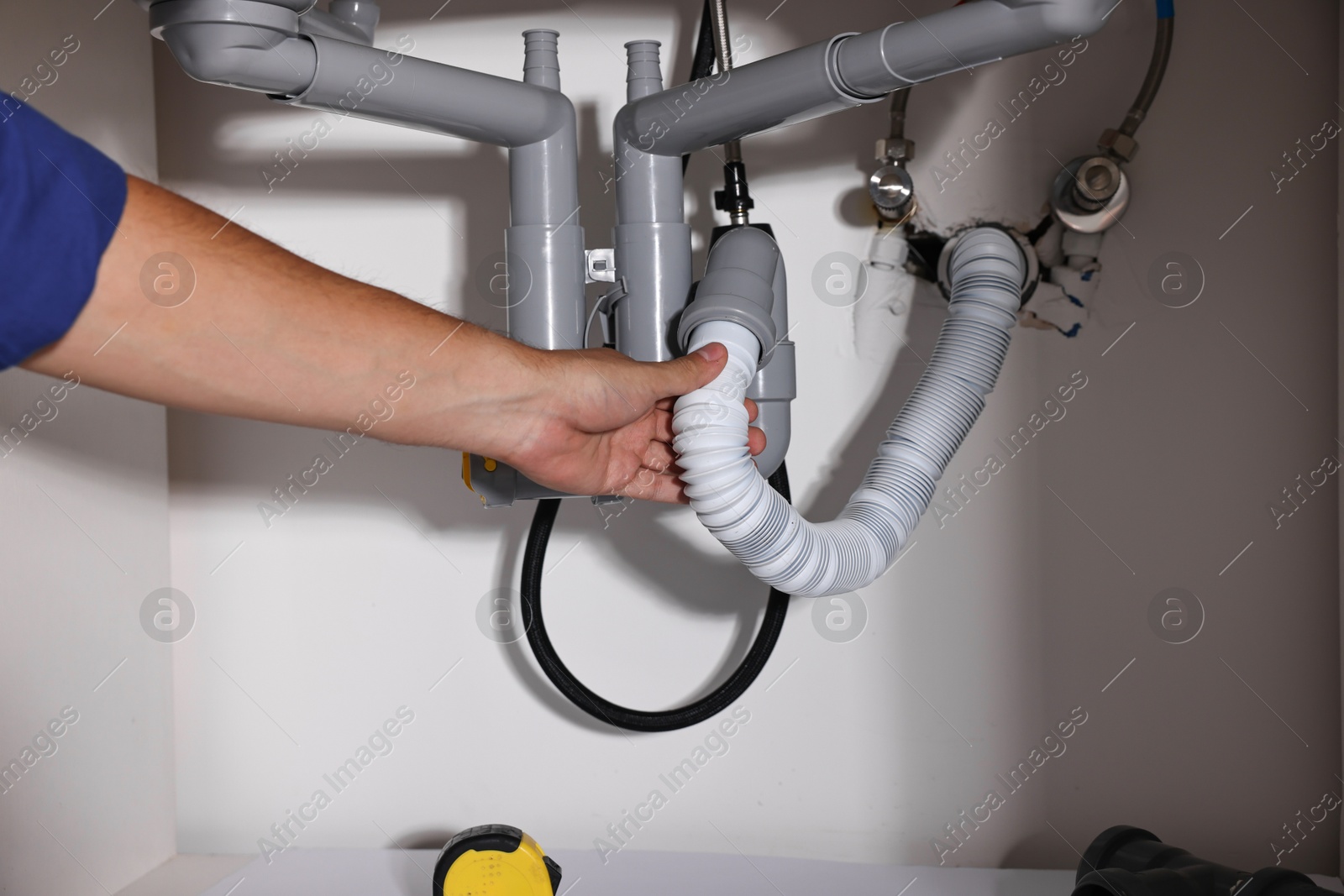 Photo of Professional plumber fixing piping system at home, closeup