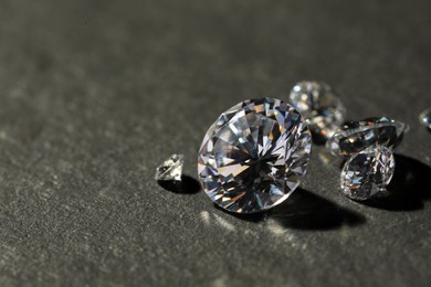 Photo of Many beautiful shiny diamonds on grey table, closeup. Space for text