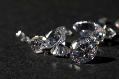 Photo of Many beautiful shiny diamonds on black table, closeup