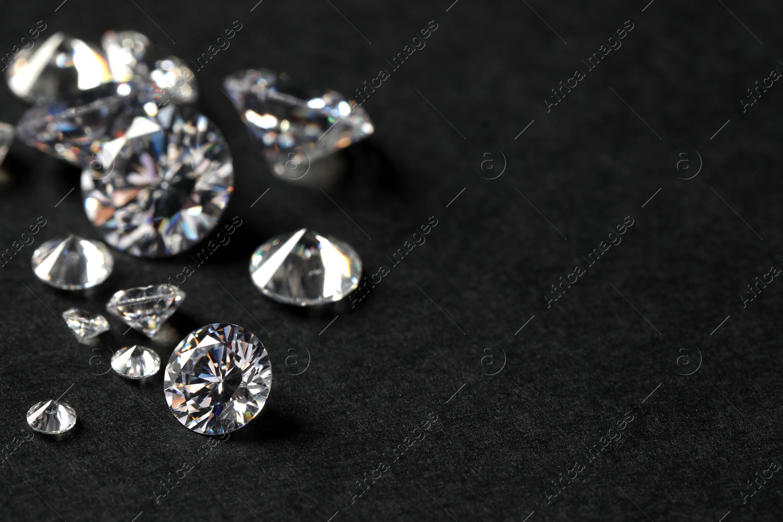 Photo of Many beautiful shiny diamonds on black table, closeup. Space for text