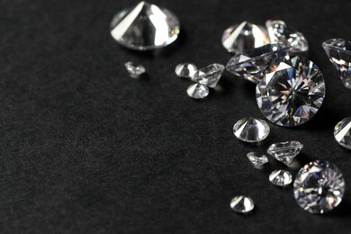 Photo of Many beautiful shiny diamonds on black table, closeup. Space for text