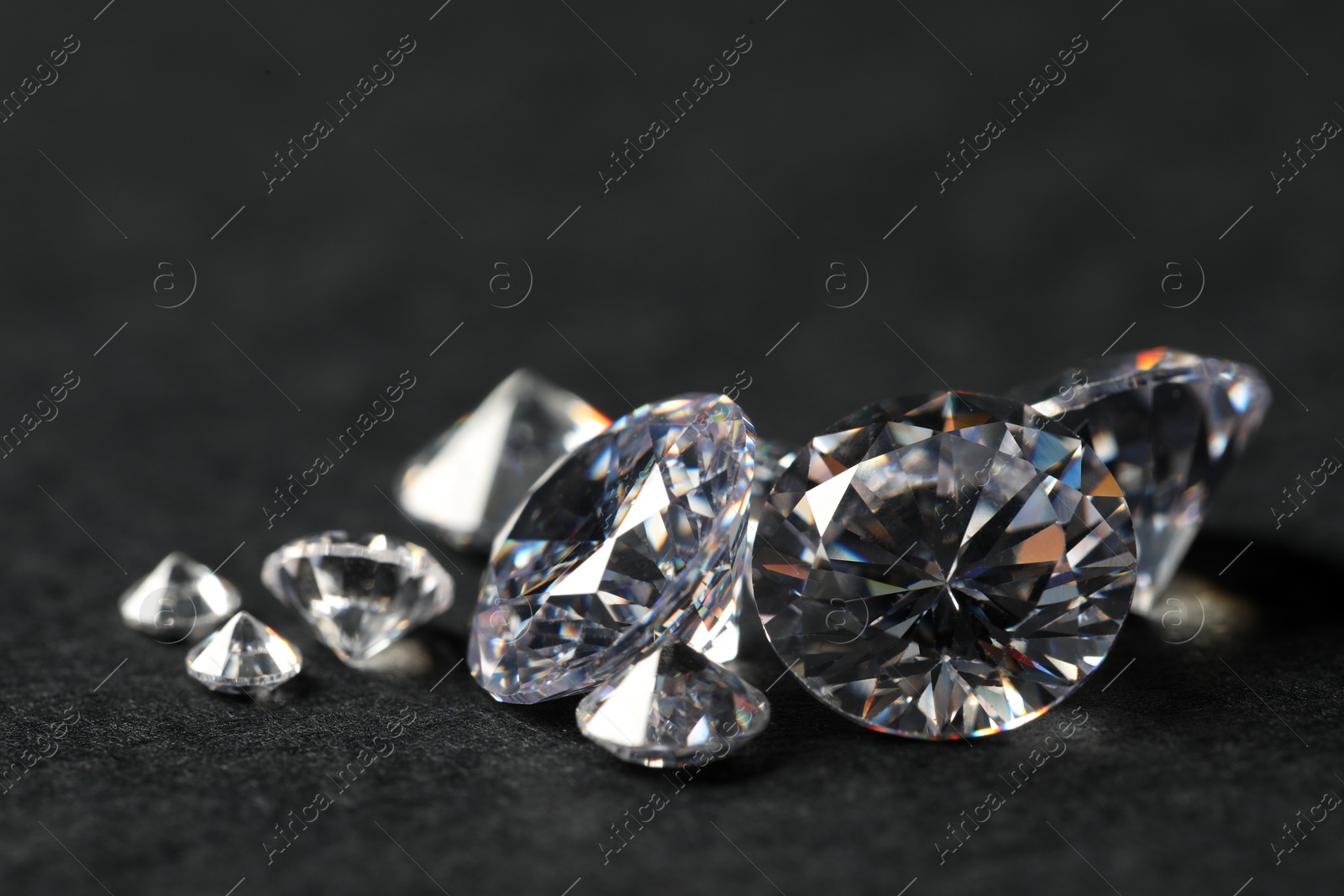 Photo of Many beautiful shiny diamonds on black table, closeup