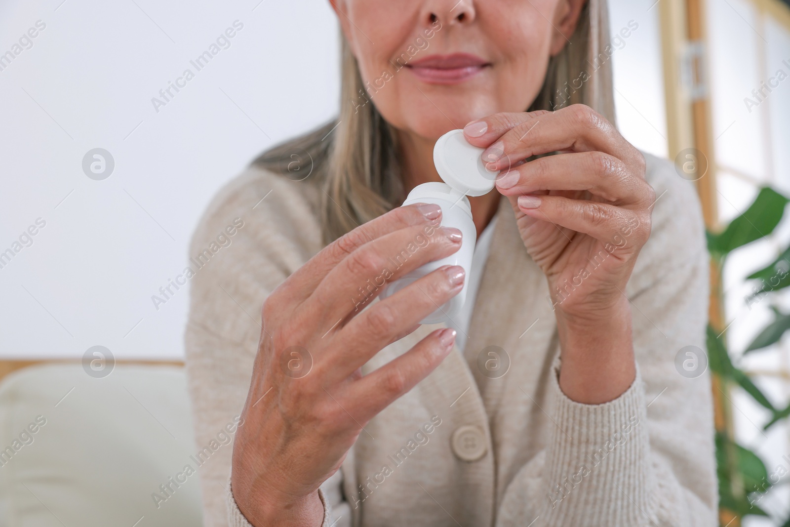 Photo of Senior woman with bottle of pills at home, closeup