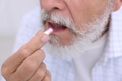 Photo of Senior man taking pill at home, closeup