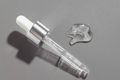 Pipette with cosmetic serum on grey background, above view