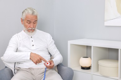 Photo of Senior man pressing emergency call button at home