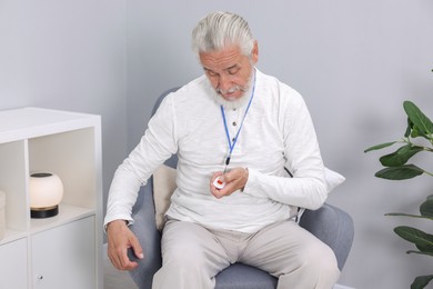 Photo of Senior man pressing emergency call button at home