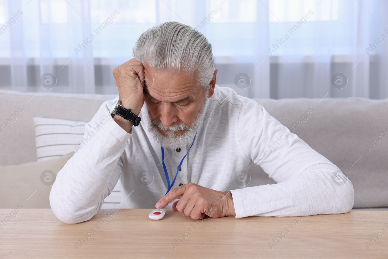 Photo of Senior man pressing emergency call button at home