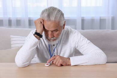 Senior man pressing emergency call button at home