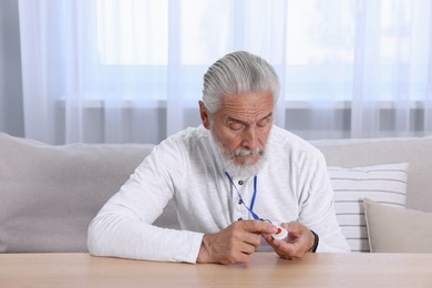 Senior man pressing emergency call button at home