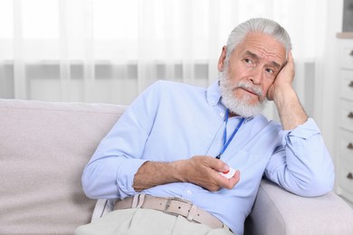 Photo of Senior man pressing emergency call button at home