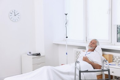 Senior man with emergency call button on bed in hospital