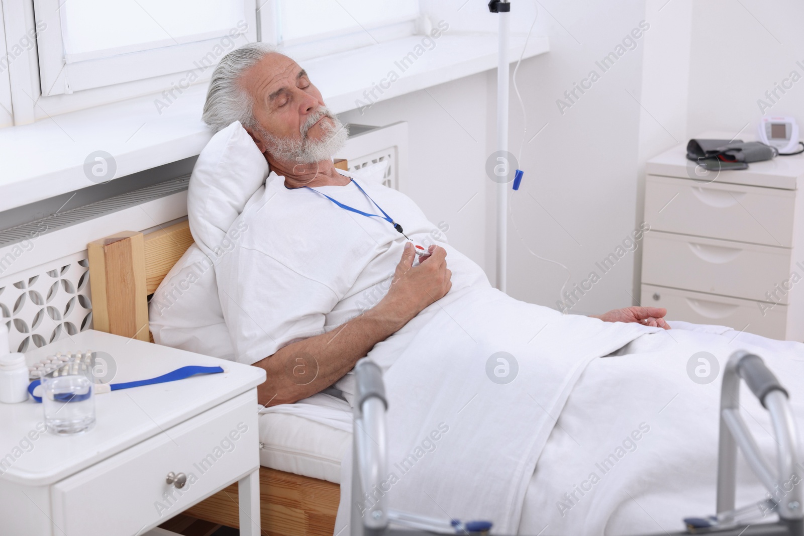 Photo of Senior man with emergency call button on bed in hospital