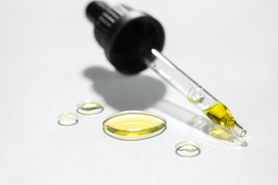 Cosmetic oil and pipette on light grey background, closeup