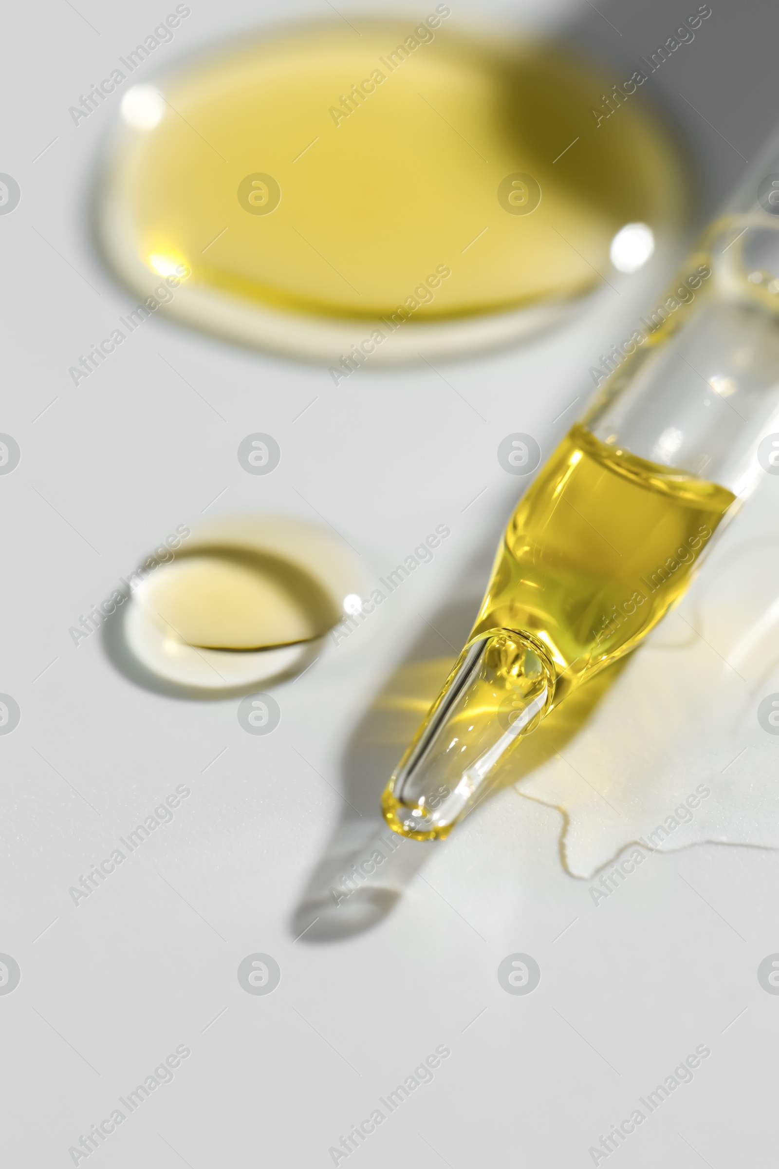 Photo of Cosmetic oil and pipette on light grey background, closeup