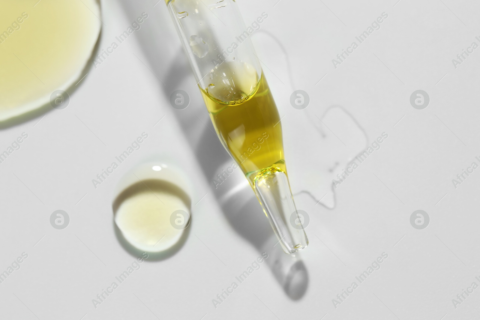 Photo of Cosmetic oil and pipette on light grey background, closeup