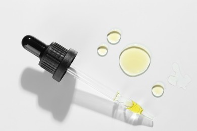 Cosmetic oil and pipette on light grey background, top view