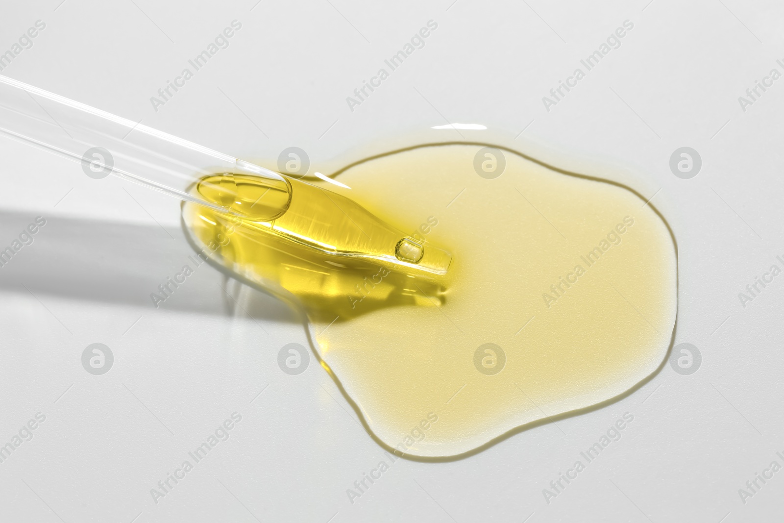 Photo of Cosmetic oil and pipette on light grey background, closeup