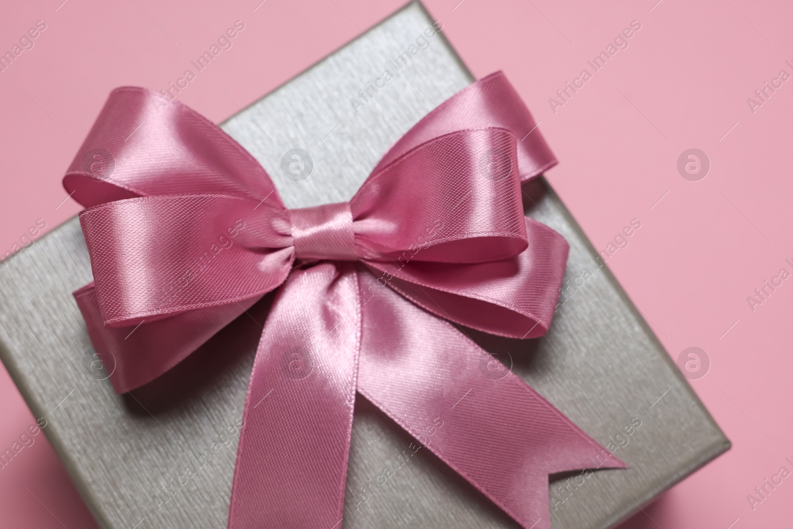 Photo of Gift box with bow on dusty pink background, closeup