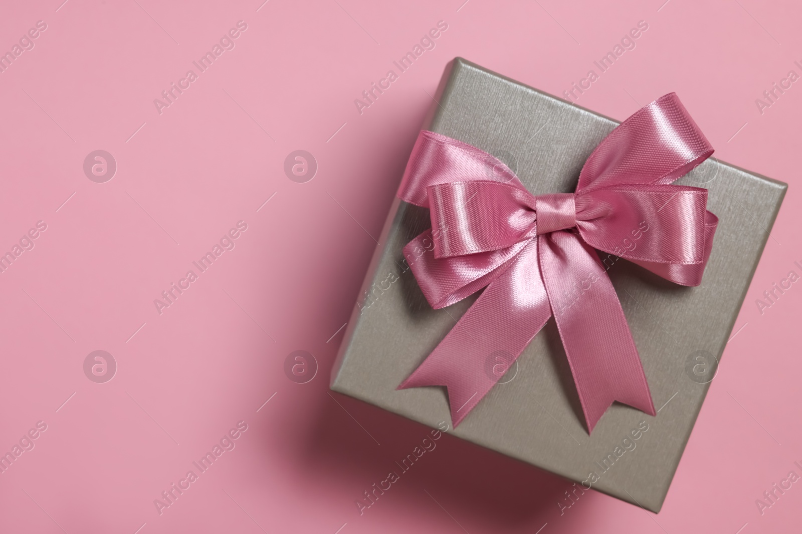 Photo of Gift box with bow on dusty pink background, top view