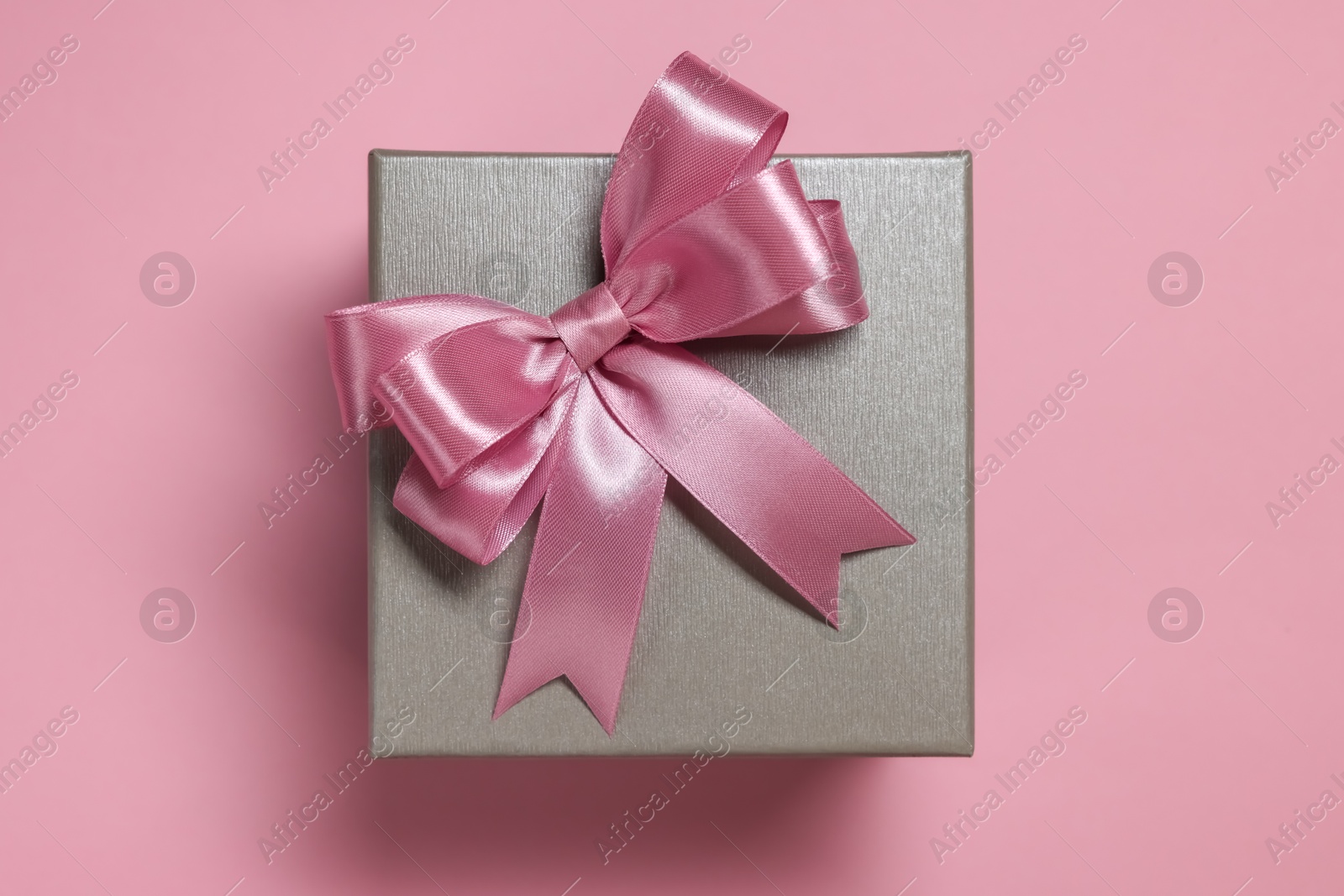 Photo of Gift box with bow on dusty pink background, top view