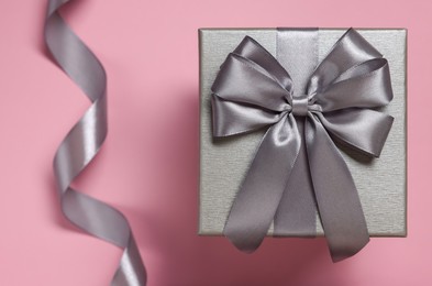 Photo of Gift box with bow on dusty pink background, top view