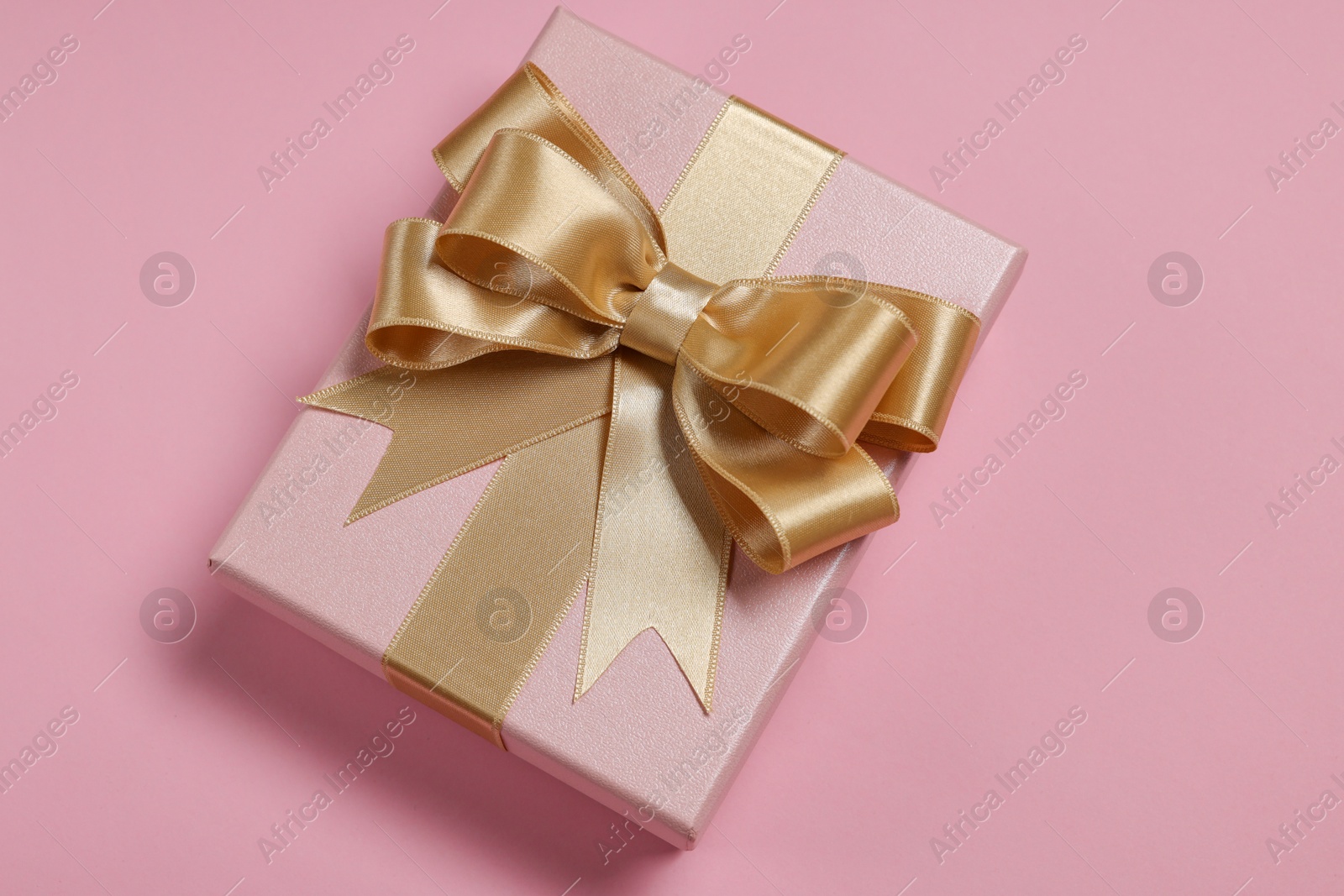 Photo of Gift box with bow on dusty pink background