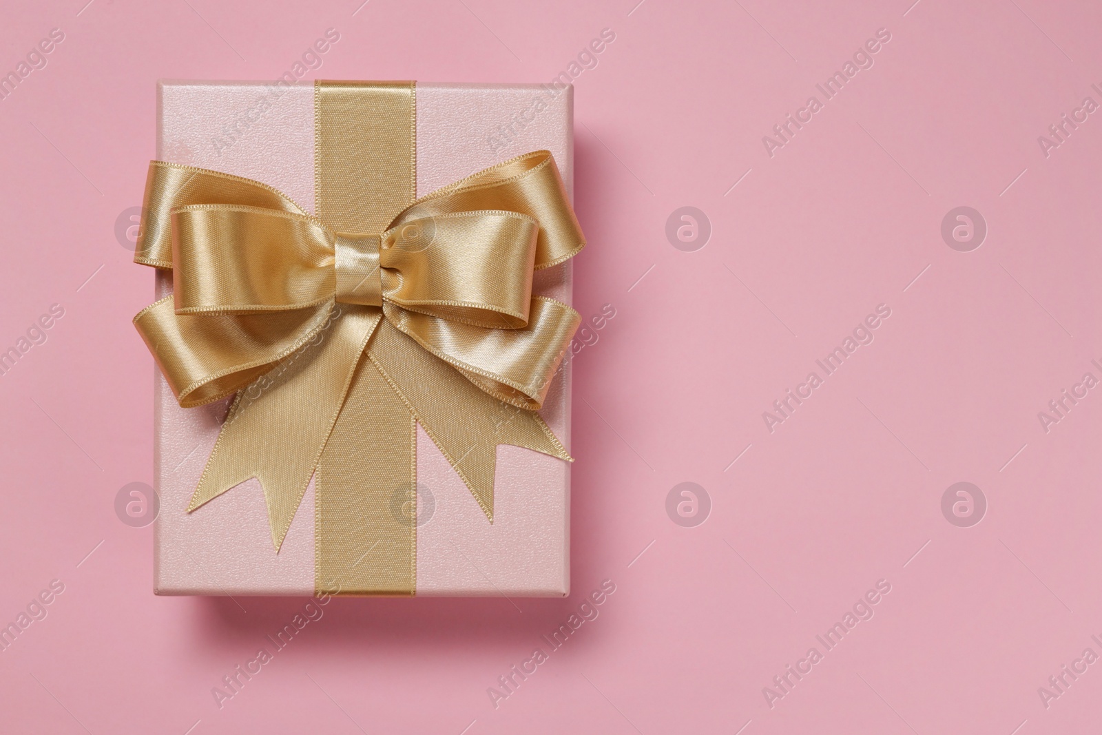 Photo of Gift box with bow on dusty pink background, top view