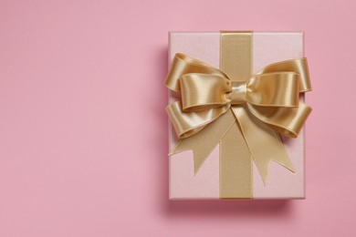 Photo of Gift box with bow on dusty pink background, top view