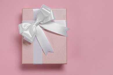 Photo of Gift box with bow on dusty pink background, top view