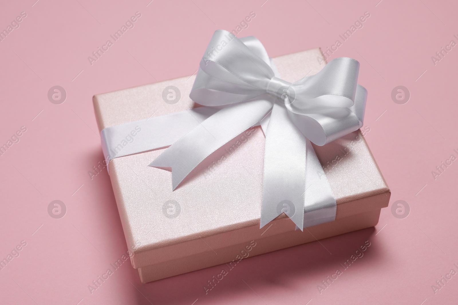 Photo of Gift box with bow on dusty pink background