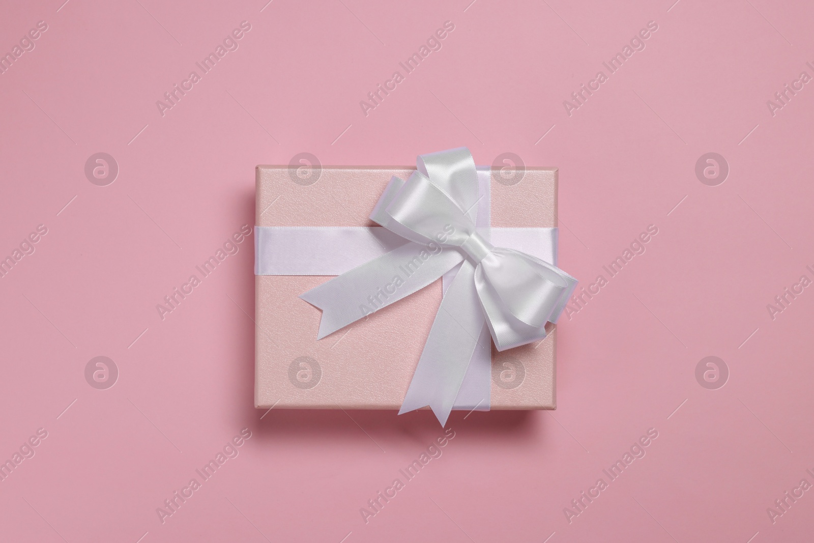 Photo of Gift box with bow on dusty pink background, top view