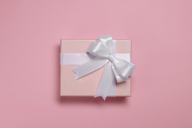 Photo of Gift box with bow on dusty pink background, top view