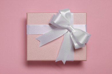 Photo of Gift box with bow on dusty pink background, top view