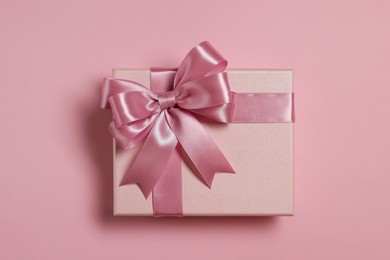 Photo of Gift box with bow on dusty pink background, top view