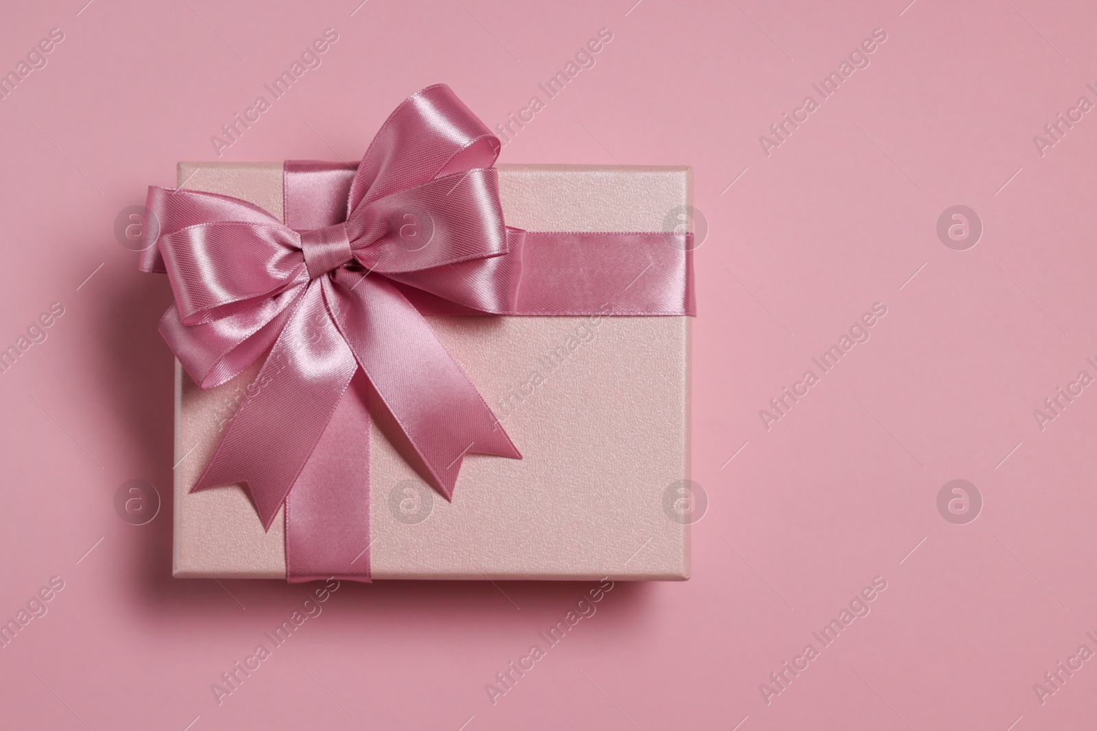 Photo of Gift box with bow on dusty pink background, top view